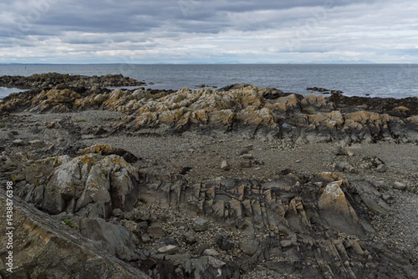 Fototapeta A rocky shoreline with a cloudy sky in the background