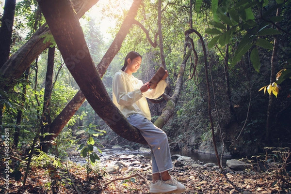 Obraz Young girl reading sitting on a tree branch