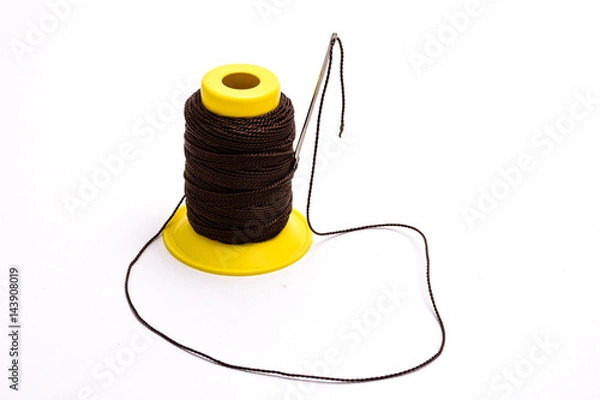 Fototapeta Thick threads and a needle on a white background, tools of a master tailor.