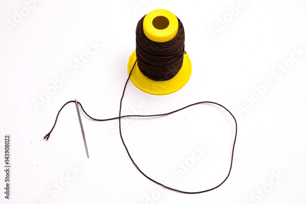 Fototapeta Thick threads and a needle on a white background, tools of a master tailor.