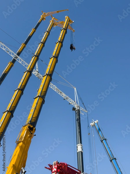 Fototapeta Construction cranes. View from below. Crane used to construct palaces, houses or buildings. Construction site. General contest