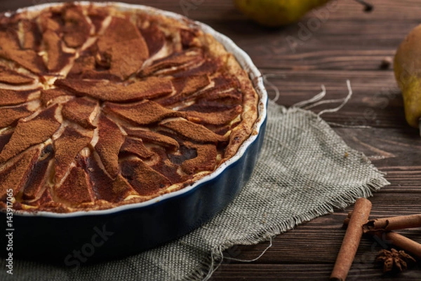 Fototapeta Fresh pear pie decorated with cinnamon and spices on a rustic wooden background
