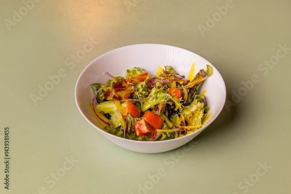 Obraz Fresh mixed salad with lettuce, tomato, red onion and honey mustard dressing.