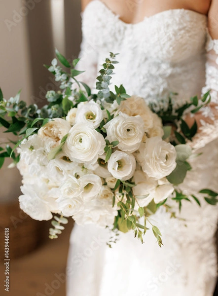 Obraz Bride holding a bouquet of white flowers in the room close-up. Beautiful wedding bouquet of white flowers, roses and eucalyptus leaves in the hands of the bride. Details of the wedding morning
