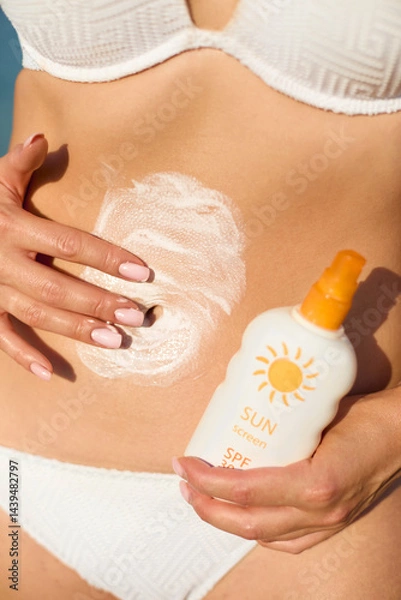 Fototapeta Applying sunscreen lotion on the skin ensures sun protection while enjoying a summer vacation at the beach, promoting healthy skin care practices.
