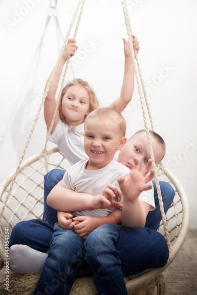 Fototapeta Children enjoy playtime on a swing, sharing laughter and joy in a cozy indoor space