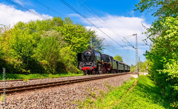 Obraz Historic steam train on the line between Bochum and Essen-Steele with an express steam locomotive of the legendary class 01 and passenger cars of a museum railroad on a sunny spring day in Germany.