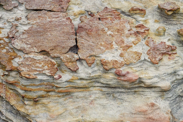 Fototapeta Eroded Stone Surface with Layered Texture in Natural Earth Tones. Close-up of weathered stone surface showing layered textures and natural earthy colors ideal for backgrounds or design use.