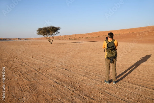 Fototapeta Man takes photo of acacia tree. Wahiba Sands. Sultanate of Oman