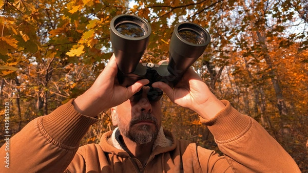 Fototapeta Amateur birdwatcher observing birds and other animals in nature with binoculars.