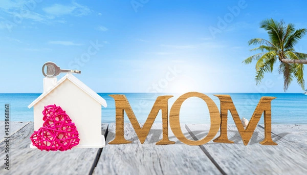 Fototapeta Mother's day card background idea, mother's day gift, mom wooden font with house model with key and heart over tropical beach