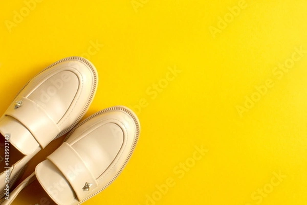 Obraz Beige shoes stand on a yellow background with space for text.
