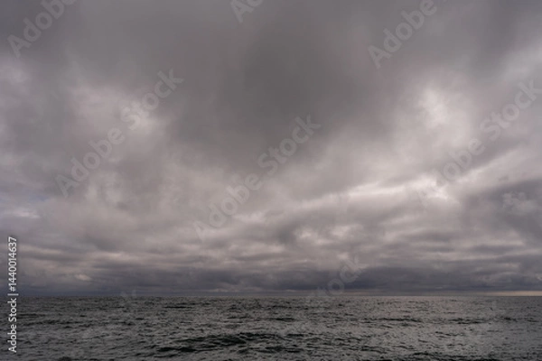 Fototapeta Dark storm clouds over ocean. Dramatic seascape. Clouds and rain flurry over sea.
