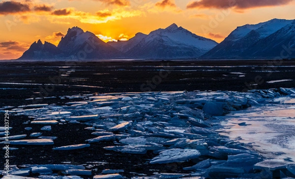 Fototapeta Outdoor scene depicting an icy river against a backdrop of snowy mountains along iceland's south coast in winter.