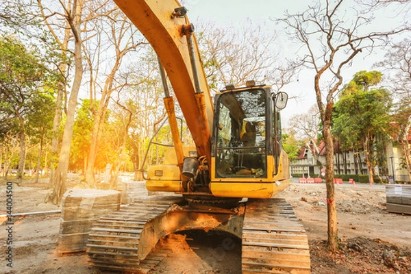 Fototapeta Excavator or backhoe at the construction site, sunset background, Track-type loader excavator machine doing earthmoving work at construction site 