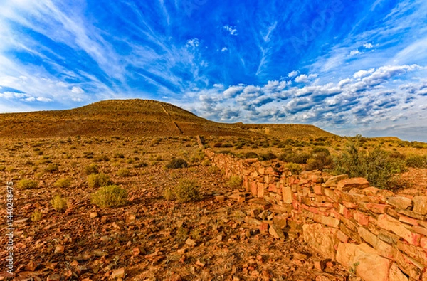 Obraz Cloudscape and landscape with barren rocky hill and an old long stone boundary wall the Biedouw Valley in the northern Cederberg, South Africa