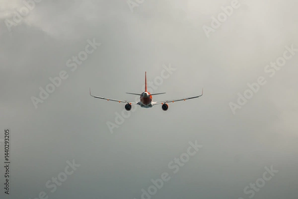 Fototapeta Flying through dense clouds an aircraft prepares for landing at dusk in a moody sky