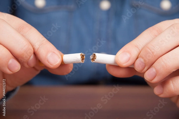 Fototapeta Frau bricht Zigarette durch