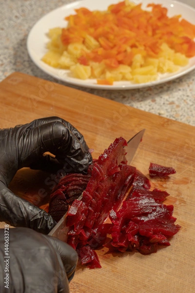 Obraz Chef's hands in gloves cutting boiled beets on a cutting board. Close-up. Cooking