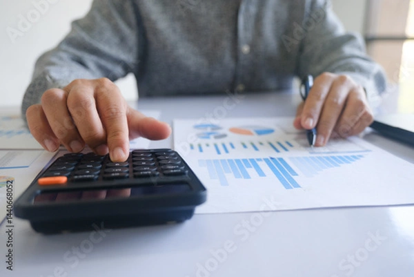 Obraz Close up accountant banker or bookkeeper making calculations with calculator.