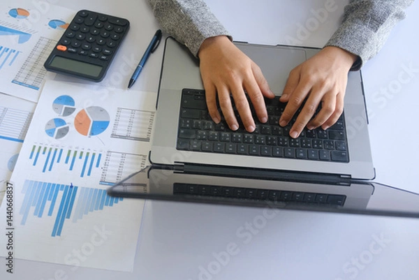 Obraz Business professional typing financial report on laptop with charts and calculator on desk
