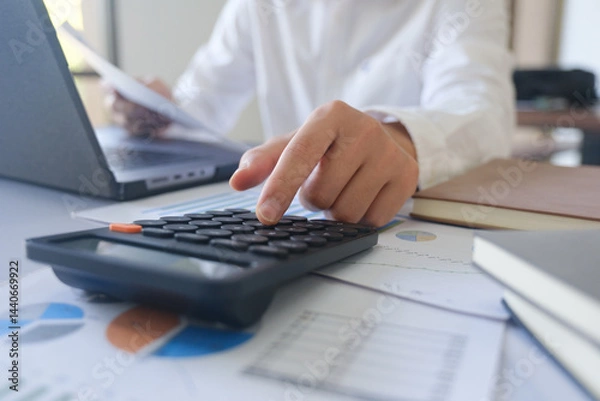 Fototapeta Close up accountant banker or bookkeeper making calculations with calculator.