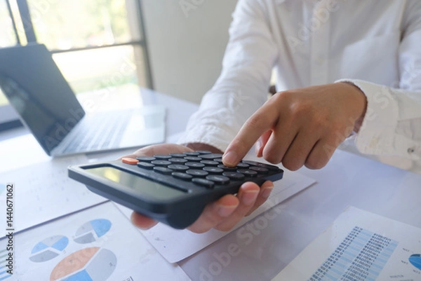 Obraz Close up accountant banker or bookkeeper making calculations with calculator.