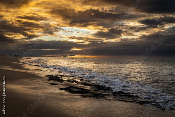 Fototapeta A huge storm on the coast gives a gloomy look and a clearing that allows you to see the sunset.