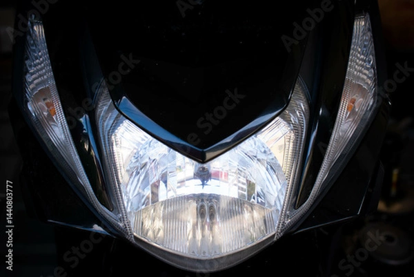 Fototapeta Close up of the main headlight design on an automatic scooter, showcasing the modern and angular shape of the lamp housing