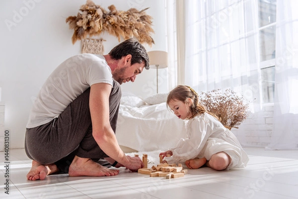 Fototapeta Father and daughter enjoying quality time together, building a structure with wooden blocks in a brightly lit bedroom, fostering creativity and connection