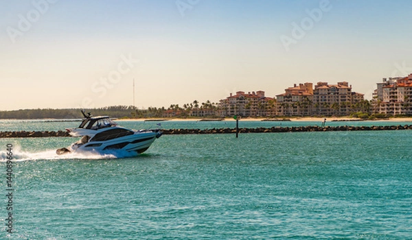 Obraz Luxury motor boat yacht. Yacht go to marina. Boating and yachting. Luxury lifestyle. Yacht at Fisher island luxury residential building. Vacation on summer. Fisher island building. Sea vacation