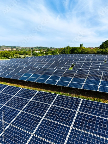 Fototapeta Rows of solar panels on farmland generating renewable and clean energy for business