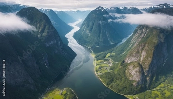 Obraz From an aerial view, the panoramic landscape shows a mountain river reflecting the sky near high rocky peaks with some mountain forests.