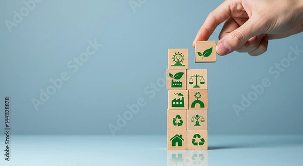 Fototapeta Entrepreneurship, startup, corporate hand placing a wooden block with a leaf icon on top of a stack of sustainability themed blocks