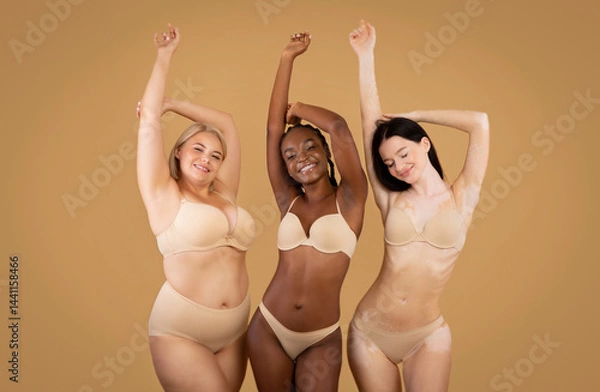 Fototapeta Love Your Body. Happy Three Women With Different Shapes And Appearance Posing Over Beige Studio Background, Positive Beautiful Multi-Ethnic Ladies In Underwear Enjoying Themselves, Copy Space