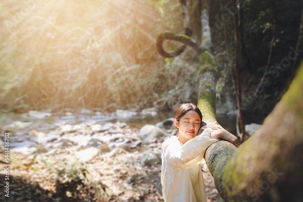 Obraz Happy teenage girl closed her dream eyes hugging a tree in the park. teenager wants a dream portrait at sunset forest.