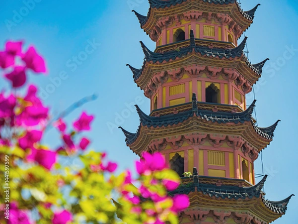 Fototapeta Colorful pagoda surrounded by vibrant flowers in sunlight captures serene beauty of the garden during daytime