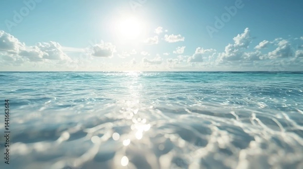 Obraz Bright sun shines over a calm, clear ocean with gentle waves and scattered clouds in a serene blue sky.