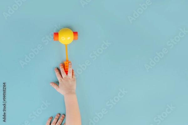 Obraz Little child's hands hold a toy hammer on the blue background. Close up, point of view shot. View from above.
