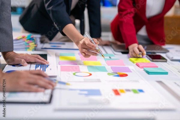 Fototapeta A group of people are working on a project and writing on a white board