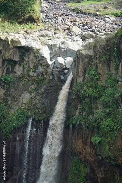 Fototapeta Majestic waterfall cascading down rocky cliffs lush greenery surrounding nature photography outdoor landscape eye-level viewpoint