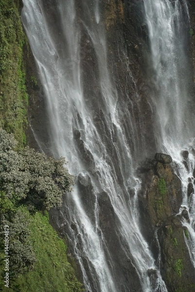 Fototapeta Majestic waterfall cascading down rocky terrain lush greenery surrounding nature photography scenic view natural beauty