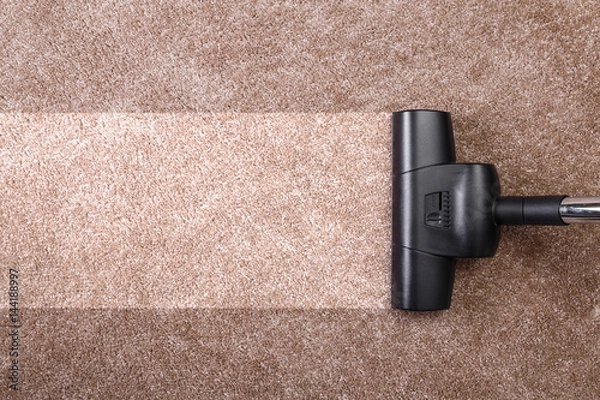 Fototapeta Vacuuming carpet with vacuum cleaner. Housework service. Close up of the head of a sweeper cleaning device.