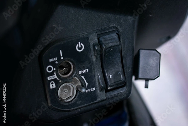 Fototapeta Close up of an ignition keyhole and control panel on an automatic scooter, showing the lock, seat, and power buttons