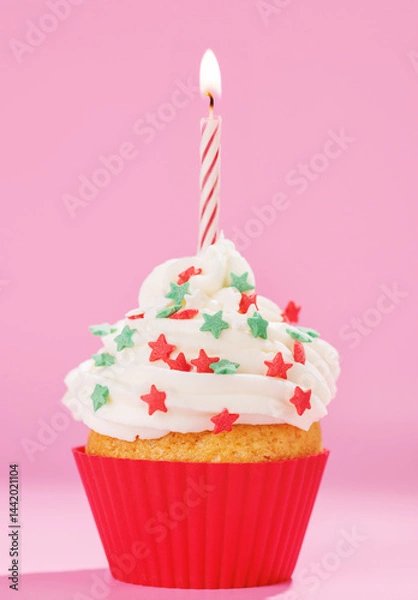 Fototapeta Festive cupcake topped with swirled frosting and a lit candle