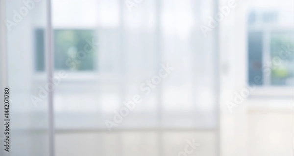 Fototapeta Blurred view of a window with white curtains and greenery outside.