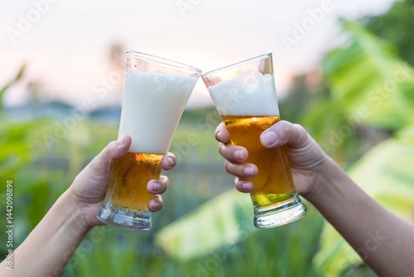 Fototapeta Close-up of hands holding a cold beer glass, condensation forming on the surface, capturing a moment of relaxation, enjoyment