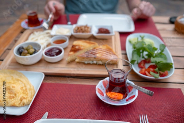 Fototapeta Traditional Turkish breakfast spread with fresh bread, olives, cheese, tomatoes, cucumbers, and variety of jams and spreads. Enjoyed in vibrant setting, capturing essence of Turkish morning culture.