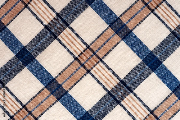 Fototapeta The texture of linen fabric in a large cage of blue, red, yellow and white. Scottish tailoring material. Checkered fabric