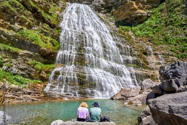 Obraz Couple in the Ordesa Valley contemplating the spectacular Cola de Caballo waterfall, Pyrenees, Spain.